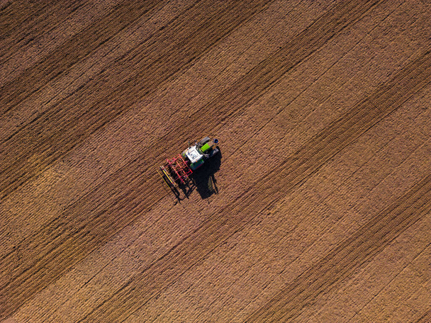 Traktorin aura pellolla kyntää maasta suoraan ylhäältä drone - Valokuva, kuva