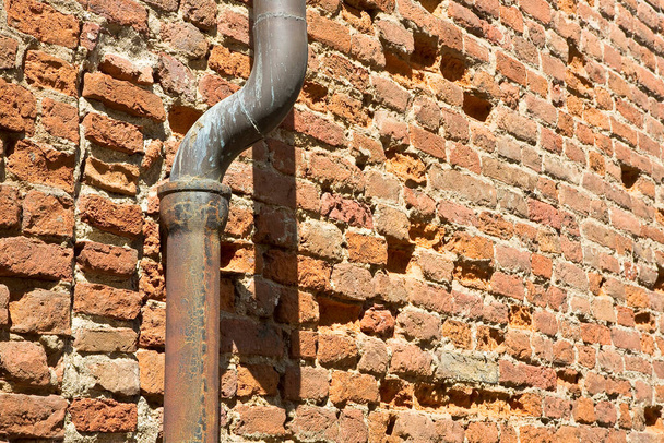 Stará rezavá měď a litina dolní trubky proti cihlové zdi  - Fotografie, Obrázek