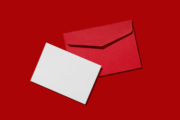 Üres fehér kártya kraft piros papír boríték piros háttér sablon mockup. Karácsonyi koncepció.  - Fotó, kép