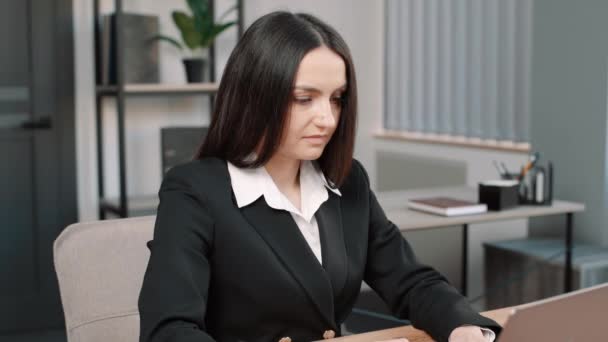 Молода ділова жінка в костюмі сидить за офісним столом з ноутбуком і показує ключі до камери - Кадри, відео