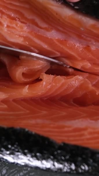 con coltello affilato tagliare grandi pezzi di pesce rosso salmone salato cottura per sushi a casa video al rallentatore - Filmati, video