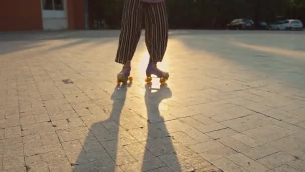 Tini lány visel fényes ruhát lovaglás lila quad görgők csinál körök szabadban nappal - Felvétel, videó
