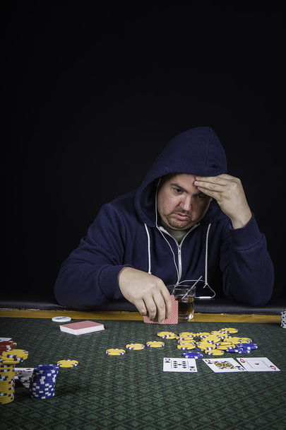 Pokeria pelaava mies istuu pöydässä
 - Valokuva, kuva