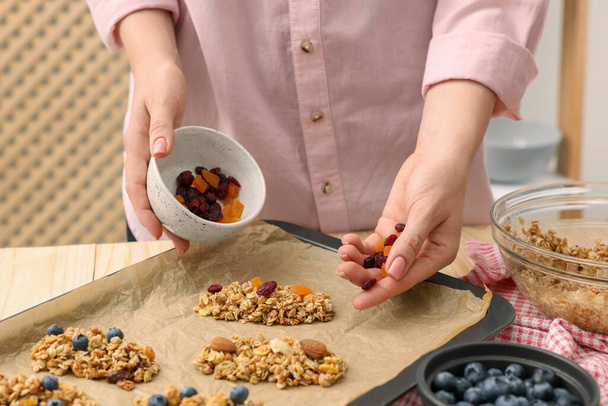 Making granola bars. Woman with dry fruits at table in kitchen, closeup - 写真・画像