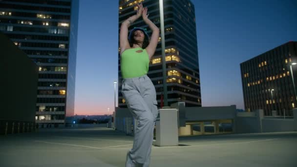Uzun kıvırcık saçlı, çatıda dans eden komik kadın şehir merkezinde eğleniyor. Canlı kamera hareketleriyle çılgın funky ruh hali, çok ırklı dansçı eğlenceli sokak tarzı seksi RNB dans hareketleri sergiliyor. - Video, Çekim