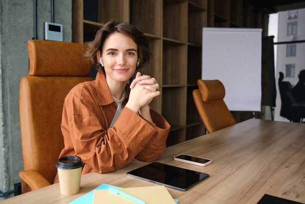 Bild einer jungen Büroangestellten, einer Angestellten in Freizeitkleidung, einer Geschäftsfrau, die am Schreibtisch sitzt und lächelt. - Foto, Bild