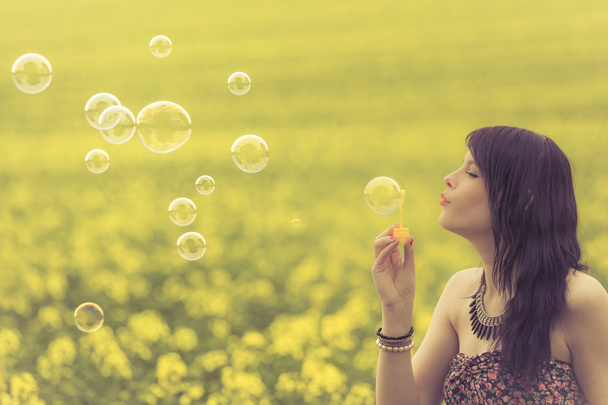 Женщина надувает много мыльных пузырей на летней природе
 - Фото, изображение