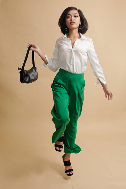 Портрет азіатської моделі моди, що демонструє аксесуар на камеру на бежевому фоні - Фото, зображення