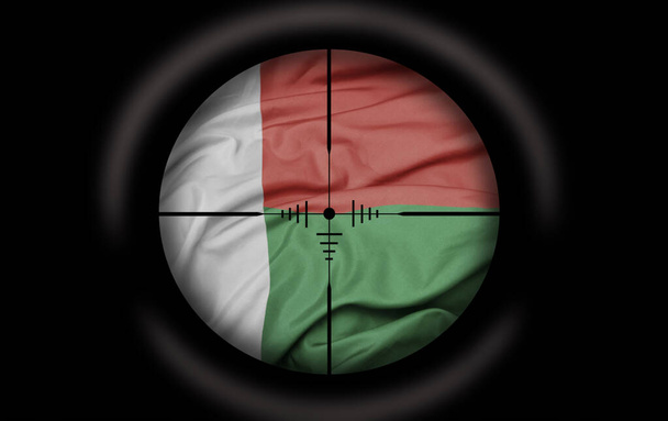 Снайперский прицел нацелен на большой красочный флаг мадагаскарской страны. концепция - Фото, изображение