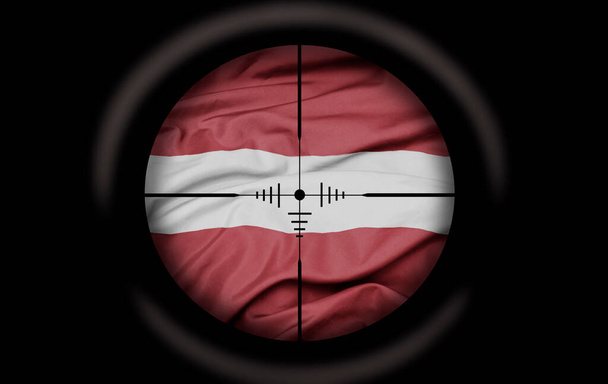 Alcance de francotirador dirigido a la gran bandera de colores del país de la latvia. concepto - Foto, imagen