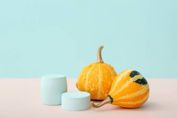Decorative plaster podiums and pumpkins on pink table against blue background - Photo, Image