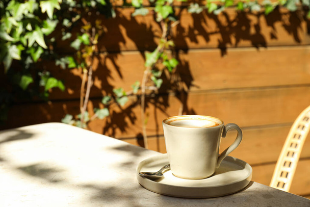 Tazza beige con caffè sul tavolo all'aperto, spazio per il testo - Foto, immagini