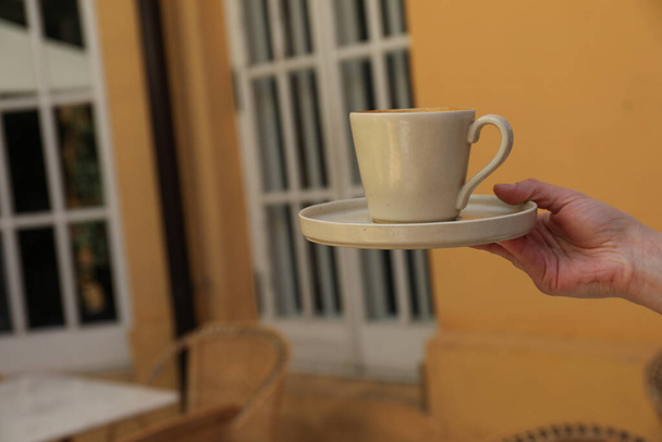 Coppa in mano su sfondo arancione parete in caffè, spazio per il testo - Foto, immagini