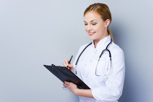 Confident female doctor writing in clipboard - Photo, image