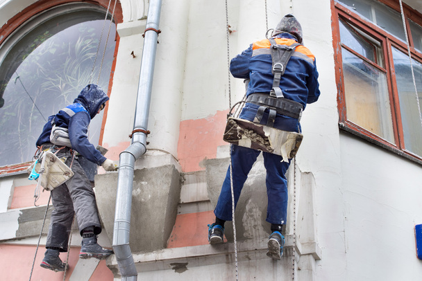 O pedreiro a trabalhar no edifício alto. Manutenção de edifícios: dois homens trabalhando em altura
. - Foto, Imagem