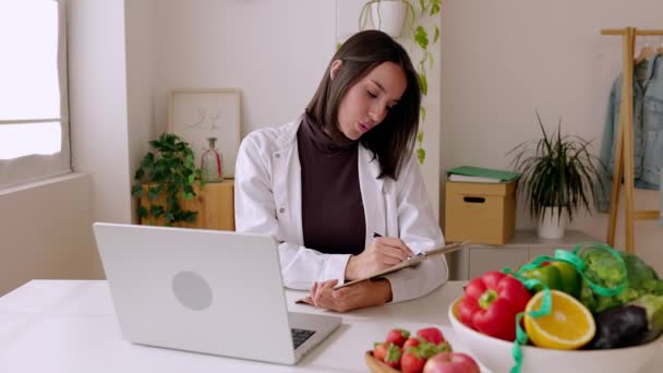 Jonge vrouwelijke voedingsdeskundige in gesprek met de patiënt via desktop computer videogesprek in de klinische spreekkamer. Gezond levensstijl, voeding en dieet concept. - Video