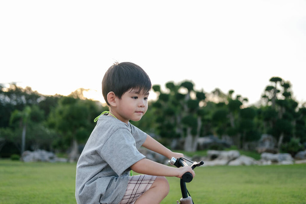 Asiático chico jugando bicicleta en el parque - Foto, imagen