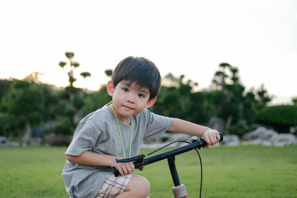 Asiático chico jugando bicicleta en el parque - Foto, imagen