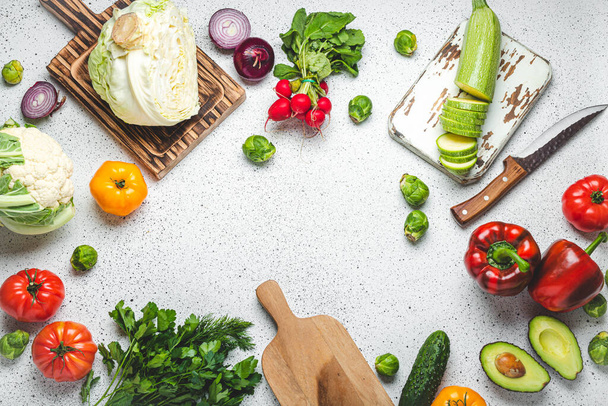 木製のまな板とナイフで新鮮な様々な野菜が白いキッチンテーブルの上からご覧いただけます。健康的な食材、食事、栄養の概念から菜食主義者の食事を調理 - 写真・画像