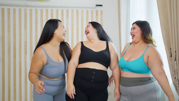 Spor giyimli, Asyalı ve cüsseli kadınlardan oluşan neşeli bir grup egzersiz yapmadan önce birlikte konuşmaktan hoşlanırlar. Mutlu tombul kadın arkadaşlar. Vücut pozitif konsept - Fotoğraf, Görsel