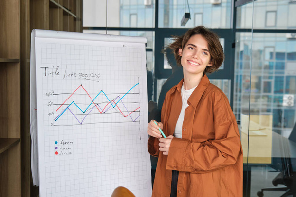 Porträt einer erfolgreichen Geschäftsfrau, modernen Managerin im Büro, neben Tafel mit Diagramm stehend, Vortrag, Rede im Konferenzraum. - Foto, Bild