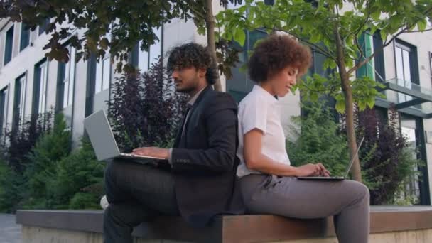 Üzleti multiracionális kollégák dolgoznak laptopok a városban indiai férfi arab üzletember afro-amerikai nő üzletasszony szabadban gépelés számítógépek mutatja hüvelykujj fel ajánlom, mint a gesztus - Felvétel, videó