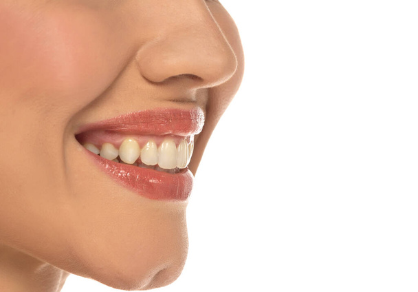 Close-up, zijaanzicht van de mond van een vrouw, het vastleggen van een zelfverzekerde glimlach en perfecte natuurlijke tanden en lippen op witte studio achtergrond - Foto, afbeelding