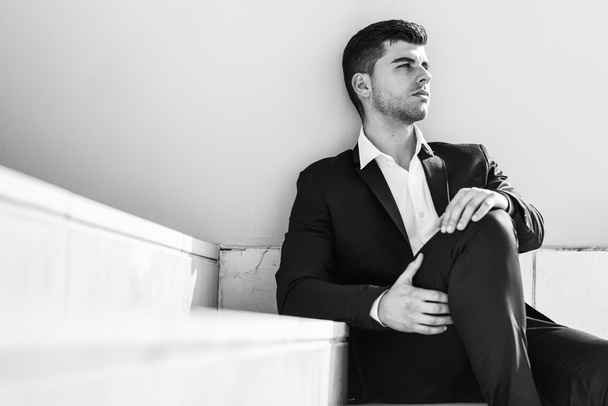 Jovem empresário perto de um prédio de escritórios usando terno preto
 - Foto, Imagem