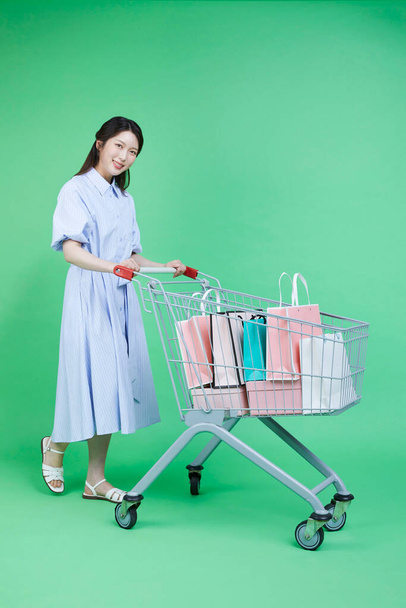 Image of green consumer, woman with shopping cart and shopping bags in cart - Φωτογραφία, εικόνα