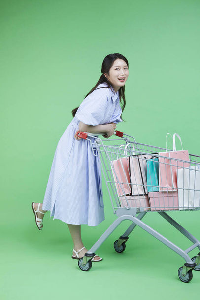Image of green consumer, woman with shopping cart and shopping bag gift box - Photo, Image