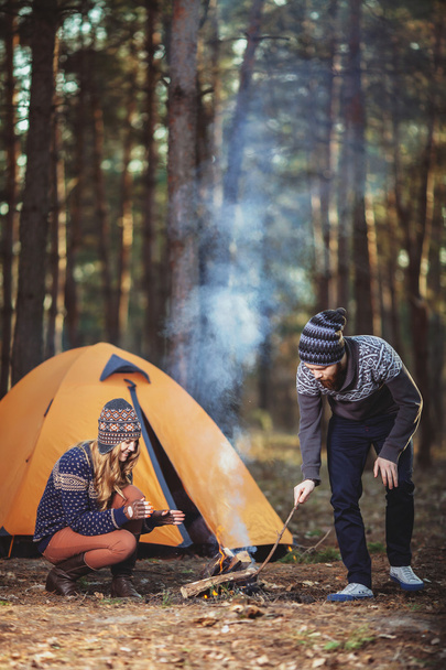 Couple of hikers starting a fire in the wood - Фото, изображение