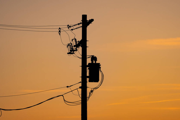 Strommastsilhouette mit Widerständen und Transformatoren auf einem Stromnetz unter einem Sonnenuntergang in Alberta Kanada. - Foto, Bild