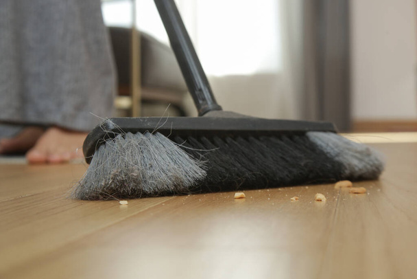 Thuis schoonmaken. close-up van vrouw doet huishoudelijk werk, het houden van een bezem en vegen vloer - Foto, afbeelding