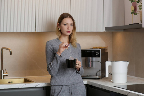 giovane donna con una tazza di tè in cucina - Foto, immagini