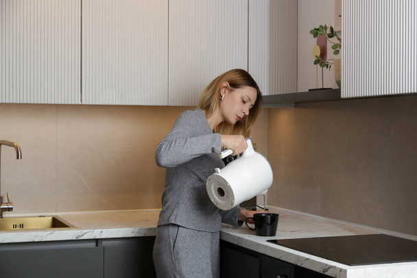молода жінка з чашкою чаю на кухні
 - Фото, зображення