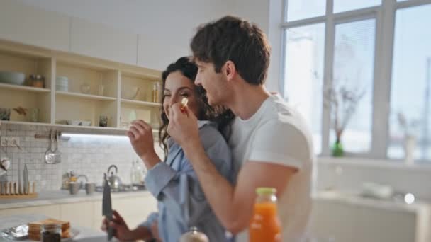 Eating happy couple cooking healthy breakfast in cozy kitchen close up. Smiling romantic partners tasting fresh apple slices preparing vegan lunch together indoors. Relaxed lovers smiling talking home - Footage, Video