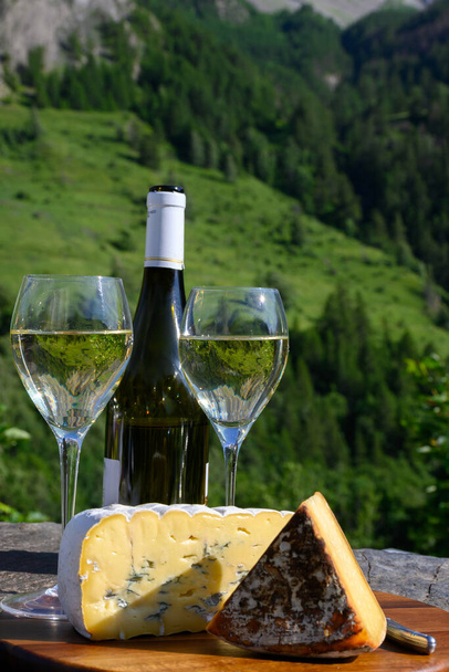 Sajt és bor, pohár száraz fehér Roussette de Savoie és Vin de Savoie bor a Savoy régió tomme sajt és kilátás nyílik Hautes Alpok hegyek hó tetején - Fotó, kép