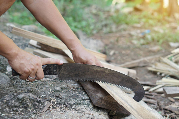 Близько людина використовує ручну пилку для різання деревини. Концепція, теслярський інструмент та будівельні вироби з дерева, ремесло ручної роботи з деревом.         - Фото, зображення