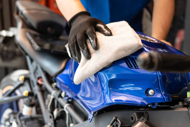 自転車を掃除するバイカーガレージで燃料タンクの研磨とコーティングワックス。オートバイのメンテナンスと修理の概念. - 写真・画像