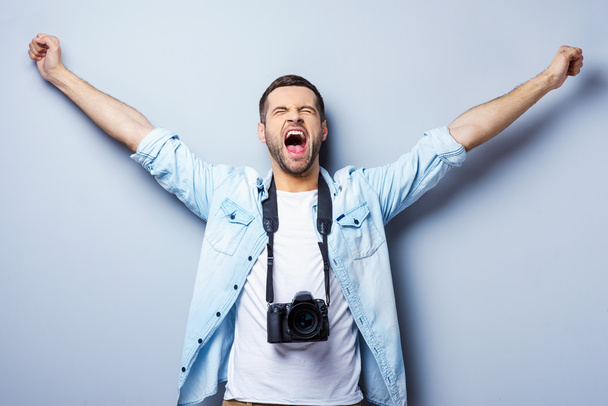 Χαρούμενος νεαρός με ψηφιακή φωτογραφική μηχανή - Φωτογραφία, εικόνα