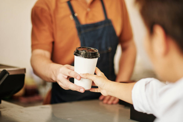 顧客にコーヒーのカップを与えるコーヒーのバリスタのクローズアップイメージ - 写真・画像
