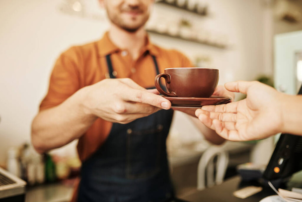 Mains de café basita donnant tasse de cappuccino au client - Photo, image