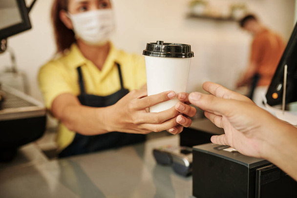Imagen de primer plano de la barista del coffeeshop femenino dando taza de café al cliente - Foto, imagen