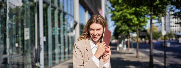 Портрет счастливой деловой женщины, улыбающейся, держащей цифровой планшет на улице возле офисного здания. - Фото, изображение