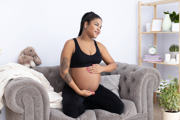 Těhotná Afroameričanka na pokoji na gauči. - Fotografie, Obrázek