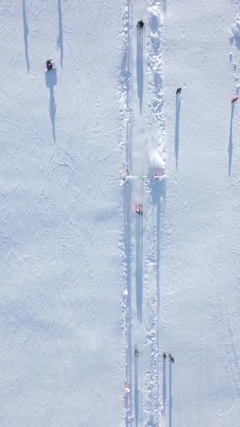Kayakçıların ve snowboardcuların güneşli bir günde kar yamacında kayak yapan kayakçıların en üst görüntüsü.. - Video, Çekim