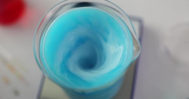 Laborchemikalien und Magnetrührer. Blaue Flüssigkeit wird in ein Glas gemischt. - Filmmaterial, Video