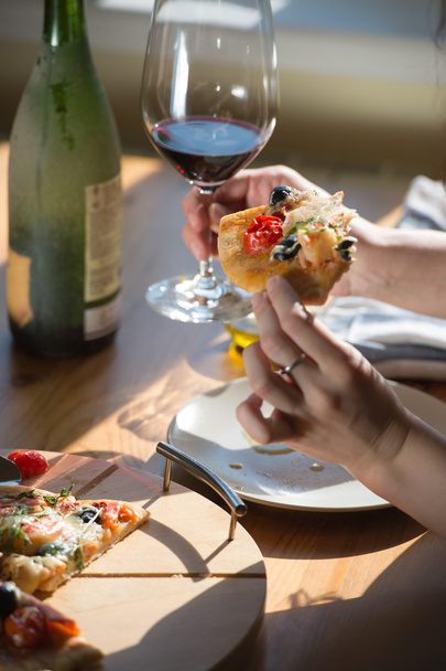 Woman eating  pizza and drinking wine - Foto, afbeelding