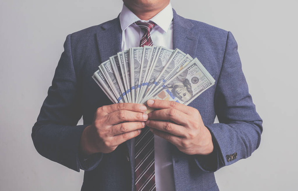Un homme d'affaires en costume tenant un billet de cent cent cent dollars. concept d'argent - Photo, image