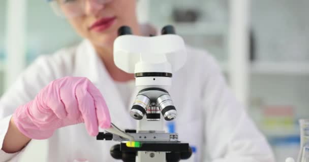 Хімік перевіряє синтез ліків в лабораторії. хімік вивчає медичні таблетки або препарати на мікроскопі - Кадри, відео
